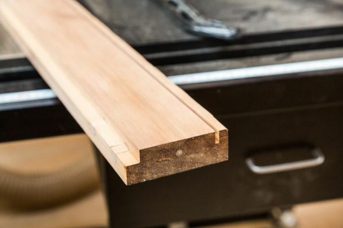Почистете дървения панел, поставен върху маса за работилници.