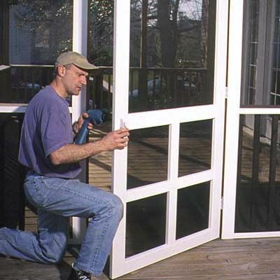 Mann installerer skjermdør på verandaen
