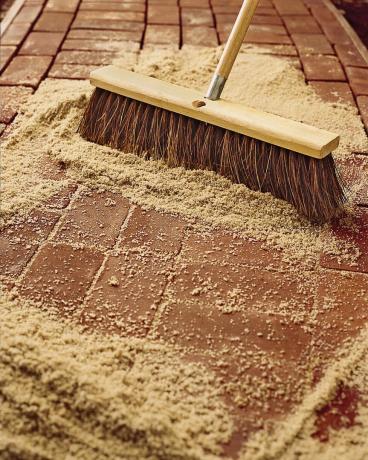 Čovjek koristi metlu za istiskivanje spojeva opeke pijeskom