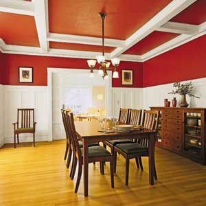 Kuchyňa s bielou výplňou, hnedým jedálenským stolom a vnútornými stenami a stropmi vymaľované červenou farbou. 