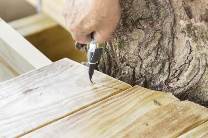 Man Scribes Short Pieces Of Deck Boards Of Tree Fort