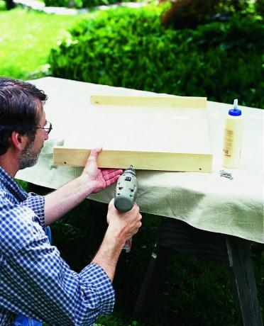 L'uomo costruisce un cassetto estraibile in legno con trapano