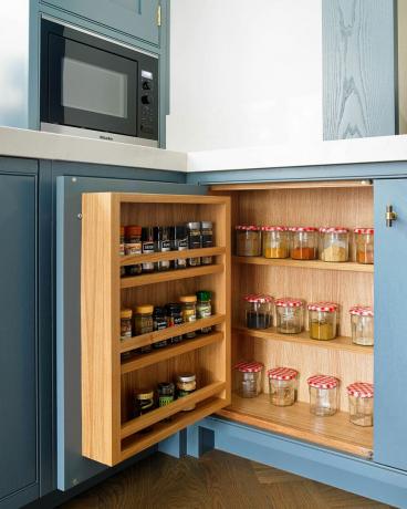 Kryddor lagrade i ett blått köksskåp.