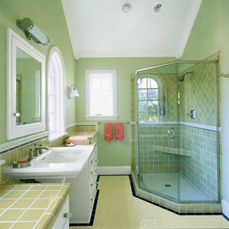 ผนังห้องน้ำสีเขียวพร้อมพื้นที่จัดเก็บเพิ่มเติมในรูปแบบของลิ้นชักโต๊ะเครื่องแป้ง 