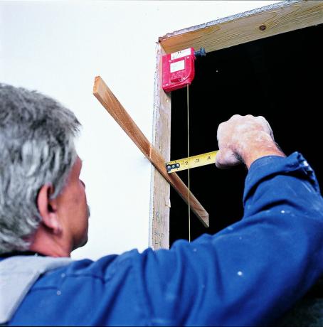 Mann som måler med loddbob for å plassere mellomlegg