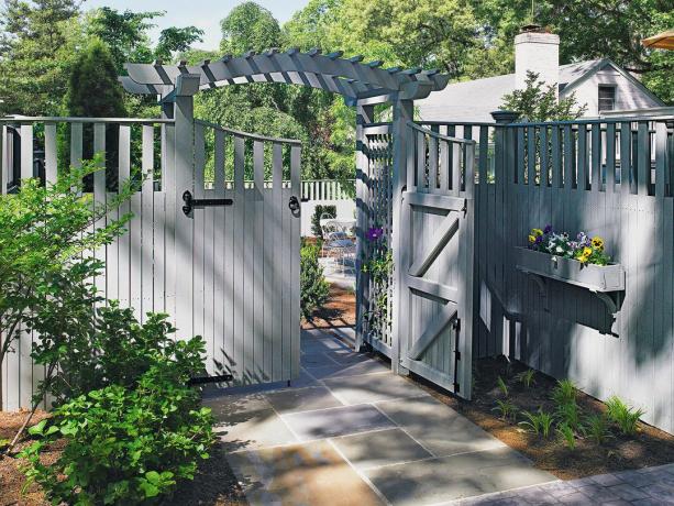 Un gard alb-gri decorat cu cutie de jardiniere și plante pentru intimitatea curții.