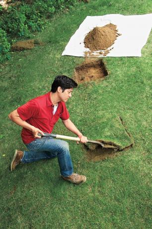 Mann graver opp jord for å plassere plantebasen i bakken