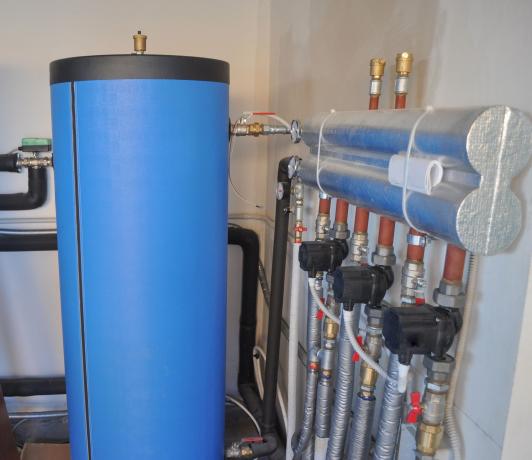 Una pompa di calore geotermica blu all'interno di una casa vicino a tubi d'argento. 