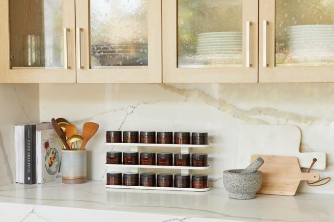 Moderní stojan na koření v jantarových lahvích sedí na moderní kuchyňské lince. 