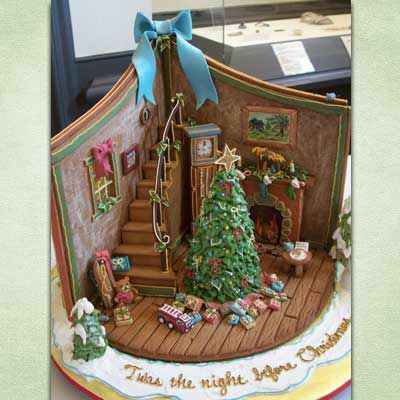 Lebkuchenkreation, die das Innere eines Hauses mit einem Weihnachtsbaum neben einer Lebkuchentreppe zeigt.