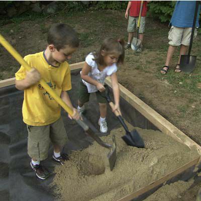 Barn fyller sandkassen med sand