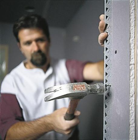 Man Hammers Nail in Corners Of Drywall