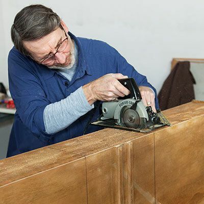 L'uomo taglia il cassetto con la sega per rifinire per creare un comò da bagno