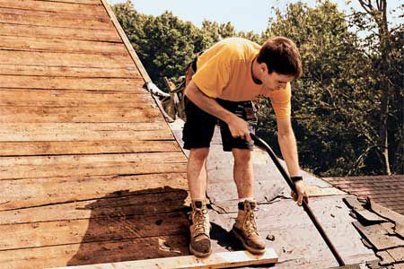 Uomo che rimuove il vecchio rivestimento del tetto