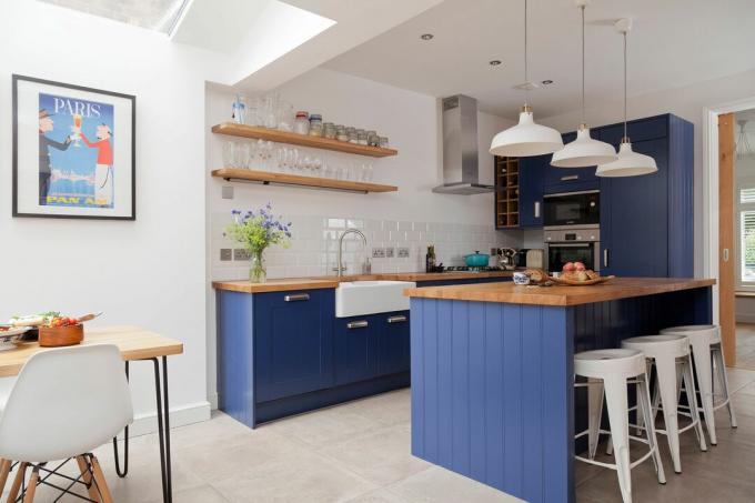Una pequeña cocina con una isla pintada de azul que permite que el espacio sea más abierto que una cocina de galera tradicional. 