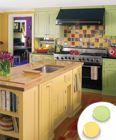 Monivärinen keittiön värimaailma vaaleankeltaisella keittiösaarella ja vihreillä kaappeilla.