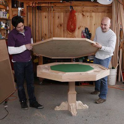 Dos personas colocan una tapa de madera contrachapada sobre la mesa de fieltro para armar una mesa de póquer de bricolaje.