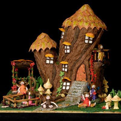 Dette udførlige fantastiske honningkager træhus ligger på en kreativ scene med svampe, grønt og børn, der leger i haven.