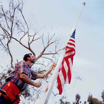 איש המרים דגל אמריקאי על עמוד הדגל