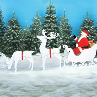 Julenissen, sleden og reintre utendørs juledekorasjon plassert i en snødekt bakgård.