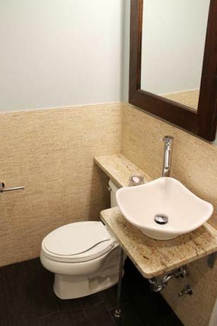 Toaleta s poličkou postavenou nad nádržou.