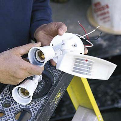 Muž montuje venkovní garážová reflektory 